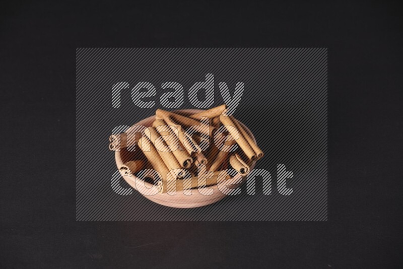 Cinnamon Sticks in a wooden bowl on black background