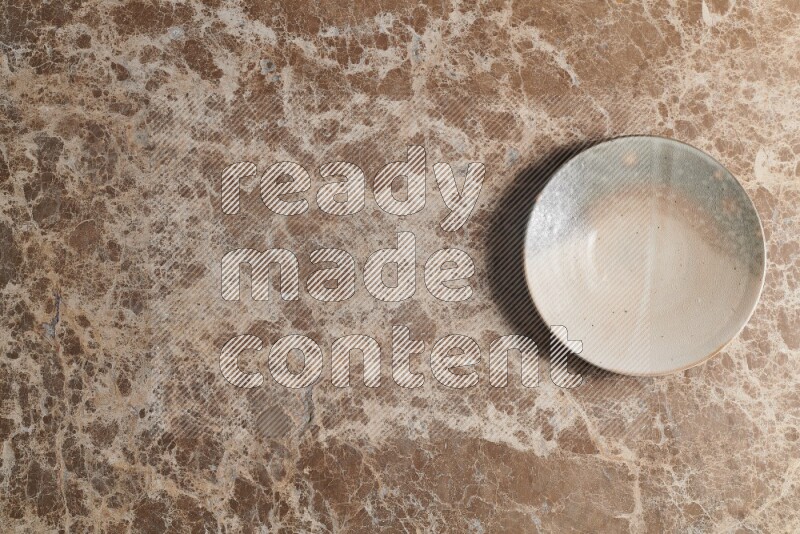 A multicolored pottery plate on beige marble background