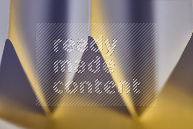 A close-up abstract image showing sharp geometric paper folds in white gradients and warm tones
