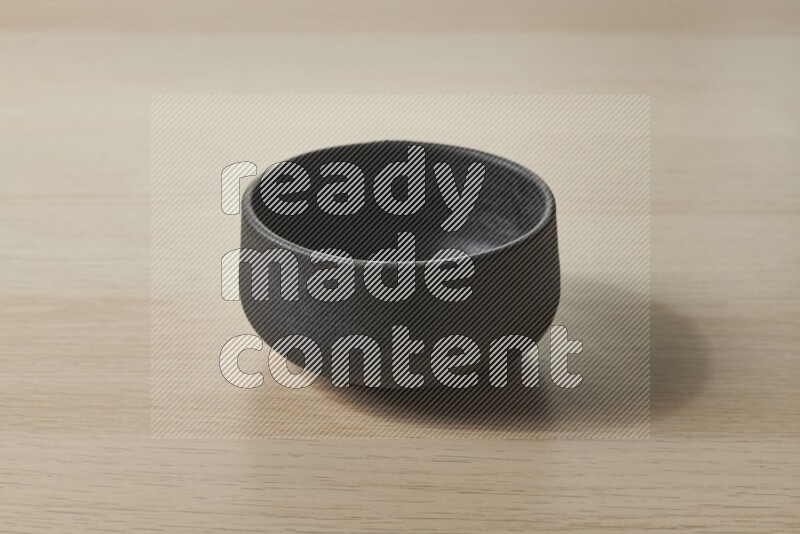 A black pottery bowl on light wooden background