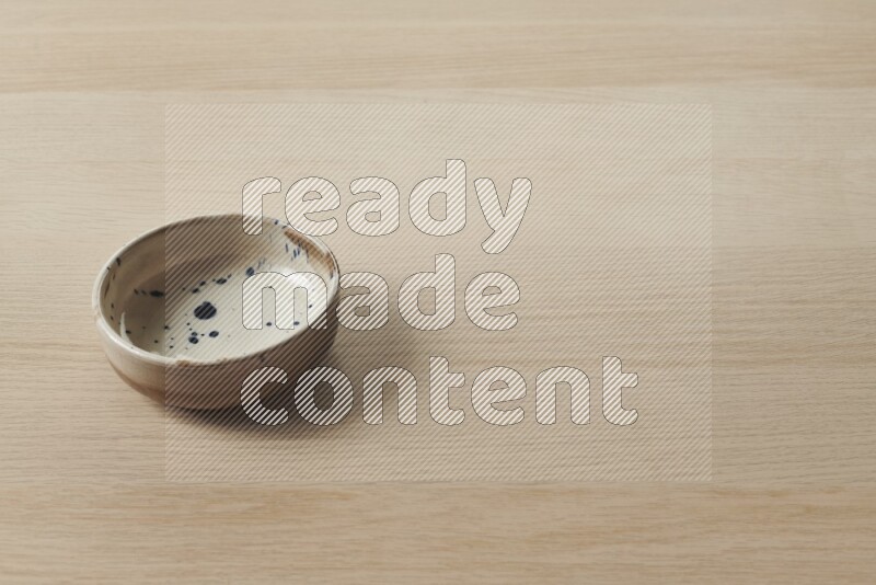 صحن فخاري متعدد الألوان على خلفية خشبية فاتحة