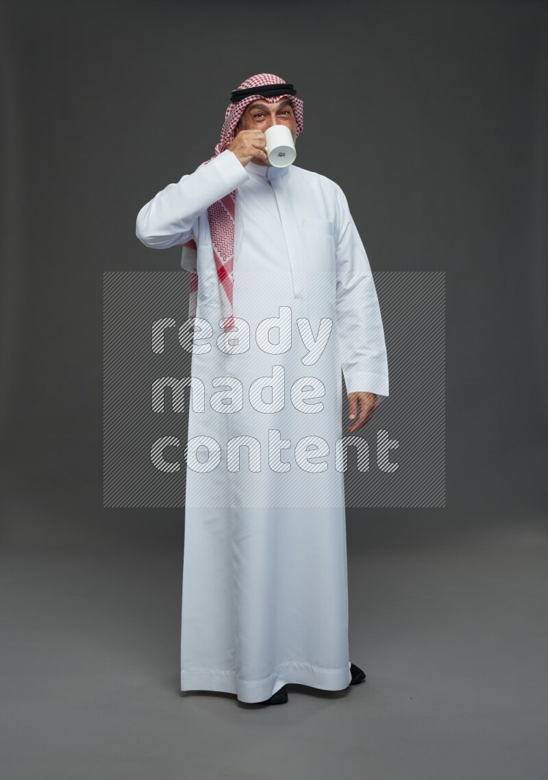 Saudi man with shomag Standing holding mug on gray background