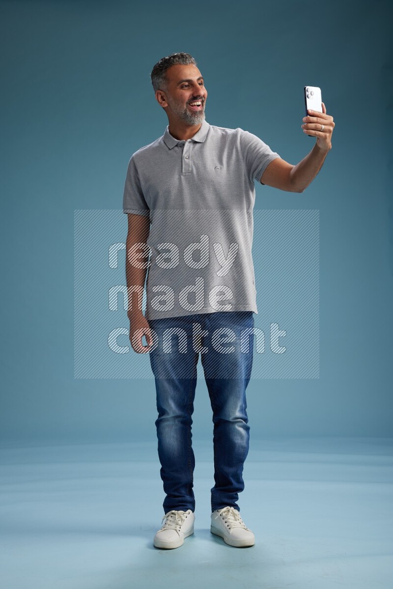 Man Standing taking selfie on blue background