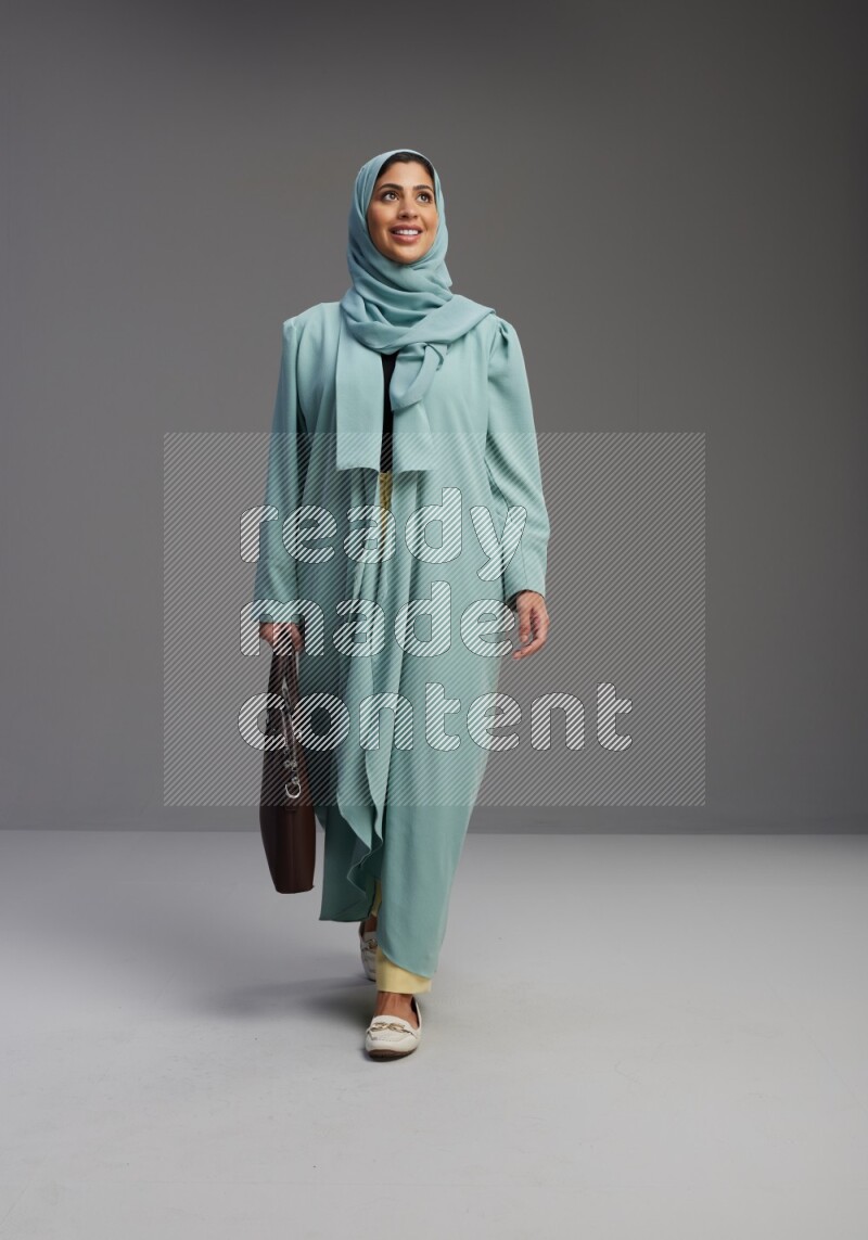 Saudi Woman wearing Abaya standing holding bag on Gray background