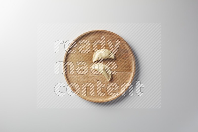 Two Sambosas on a wooden round plate on a white background