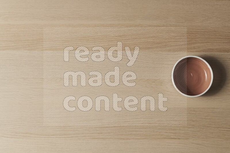 A brown pottery bowl on light wooden background