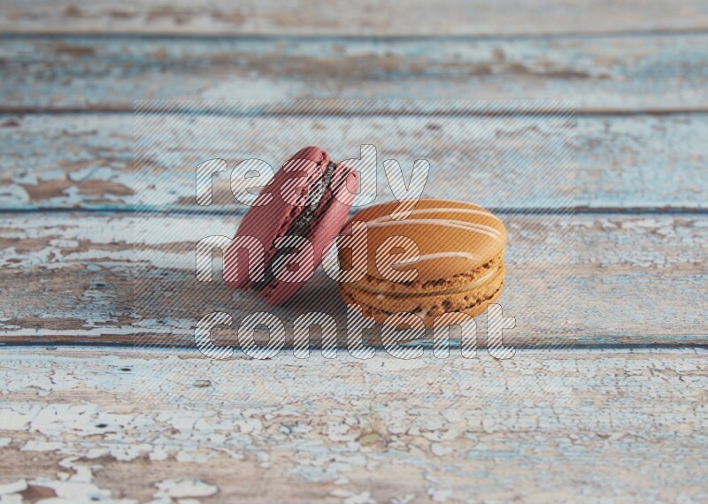 45º Shot of of two assorted Brown Irish Cream, and Red Cherry macarons  on light blue background