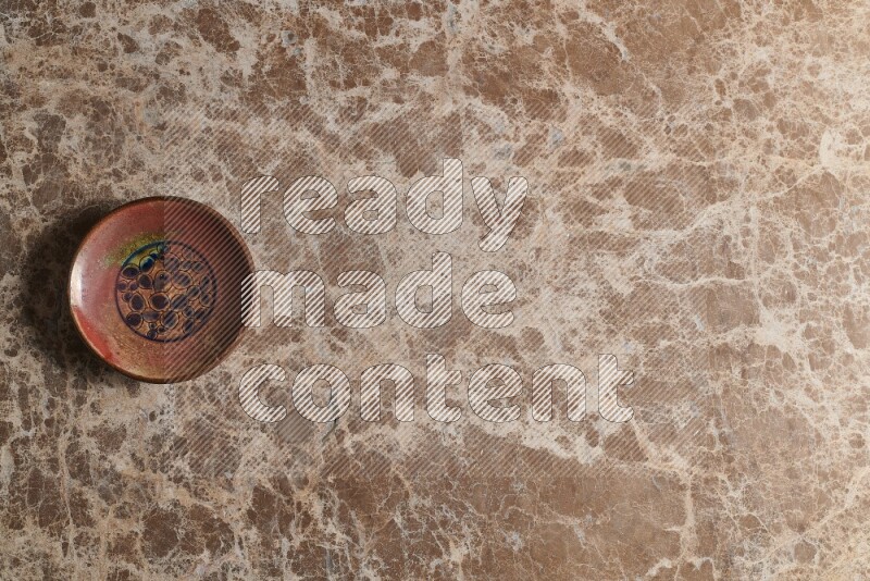 A decorative pottery plate on beige marble background