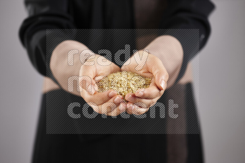 Woman in abaya holding different kinds of legumes in different positions