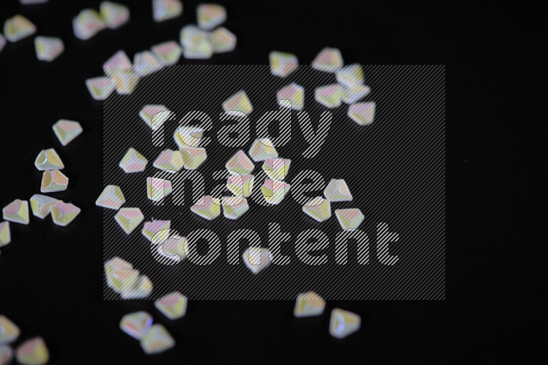Colorful plastic shards for decoration scattered on a black background