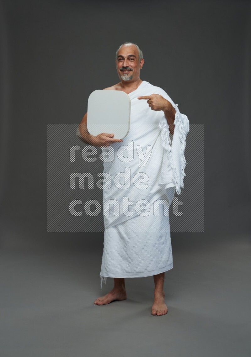 A man wearing Ehram Standing holding social media sign on gray background