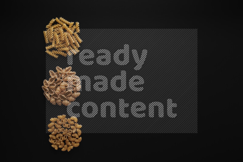 Different pasta types in 3 bunches on black background