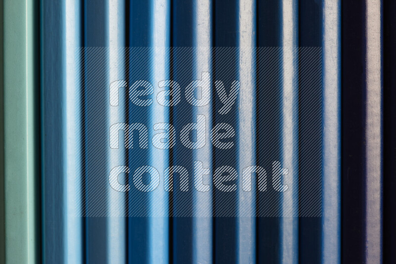 A collection of colored pencils arranged showcasing a gradient of blue hues on grey background