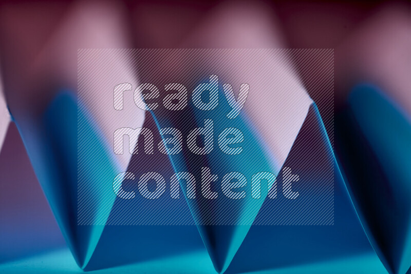 A close-up abstract image showing sharp geometric paper folds in blue and red gradients