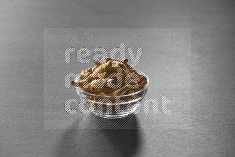 A glass bowl full of turmeric on black flooring