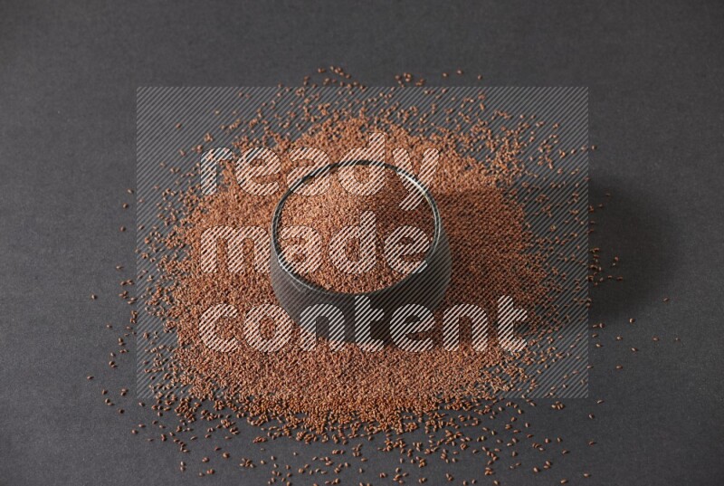 وعاء فخاري أسود ممتلئ ببذور حب الرشاد محاط بالبذور على أرضية سوداء