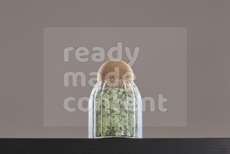 Sequins in a glass jar on black background
