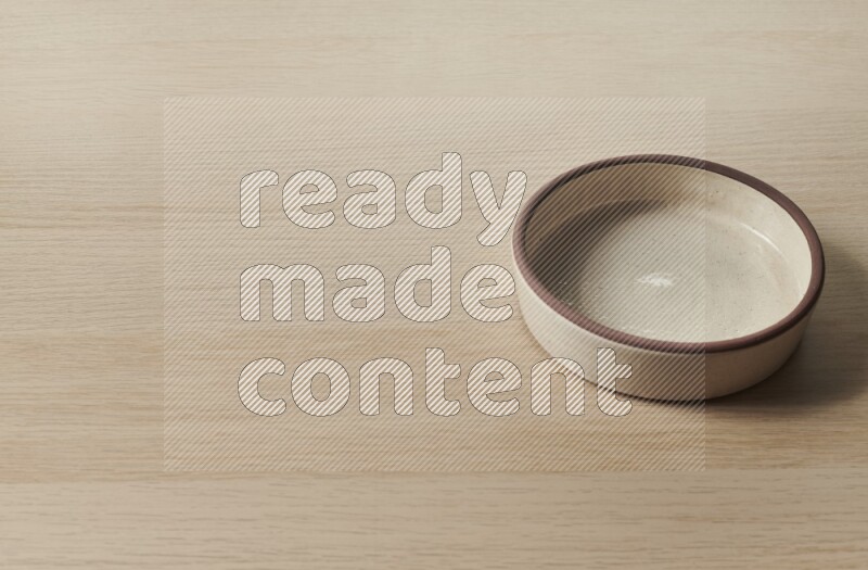 A beige pottery oven bowl on light wooden background