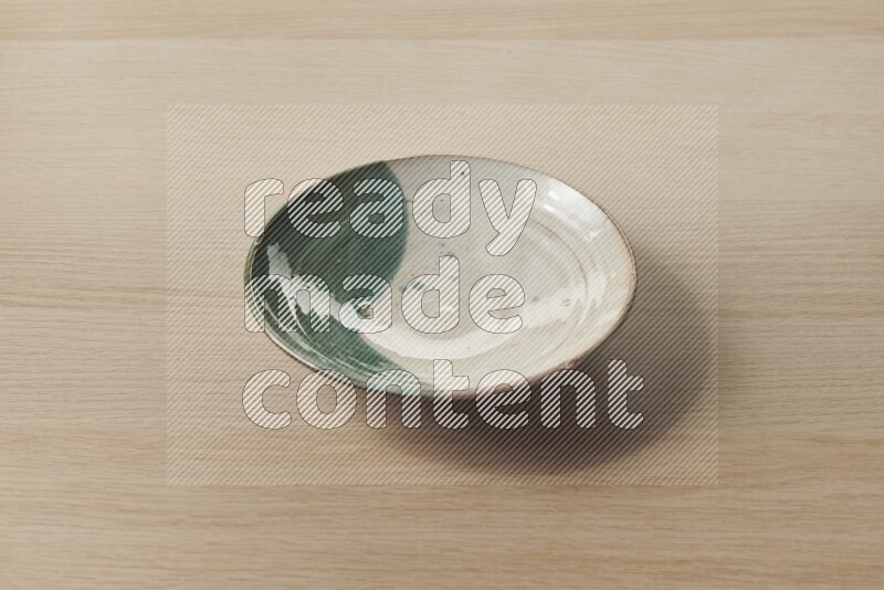A multicolored pottery plate on light wooden background
