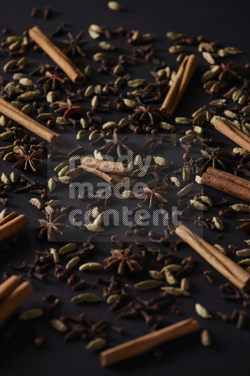 Cinnamon Sticks, Star anise, Cardamom and cloves on a black background