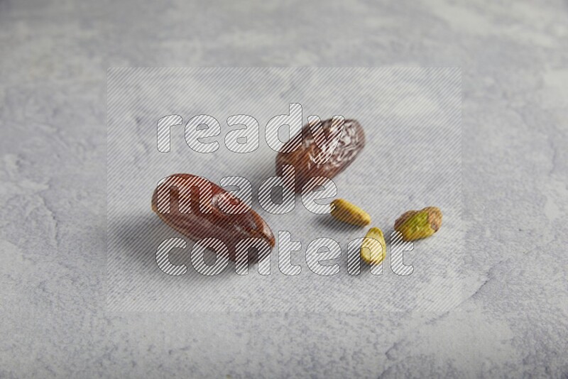 dates and unroasted pistachios on a light grey background