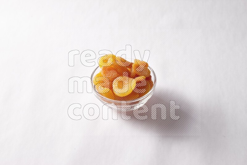 Dried apricots in a glass bowl on white background
