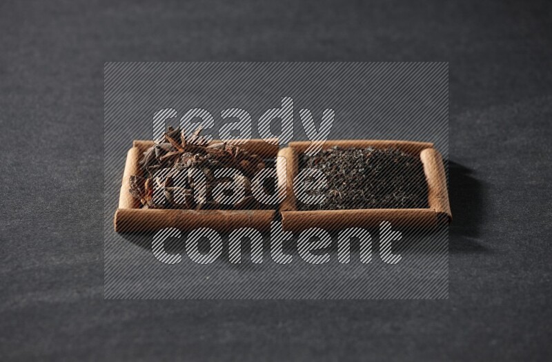 2 squares of cinnamon sticks full of star anise and black tea on black flooring