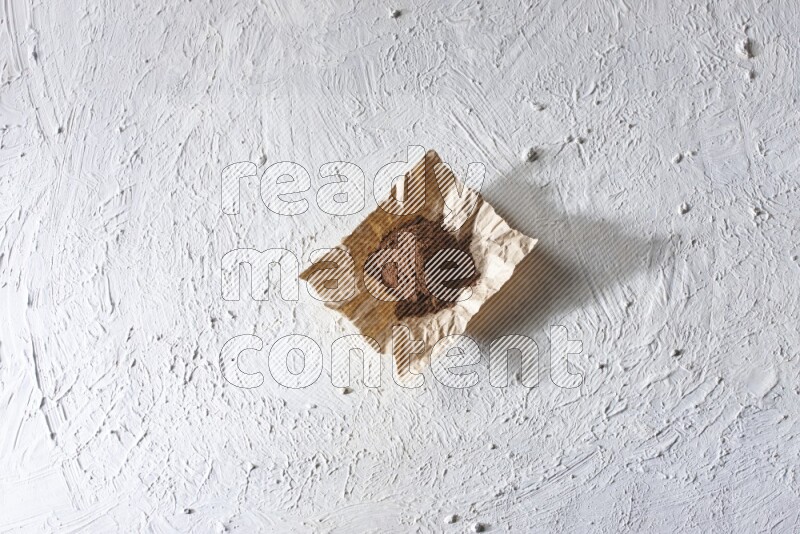 بودرة القرنفل في قطعة من الورق علي خلفية بيضاء