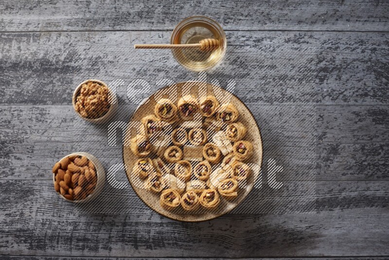 Oriental sweets in a pottery plate with nuts, coffee and honey in a dark setup