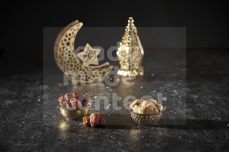 Dates in a metal bowl with dried figs beside golden lanterns in a dark setup
