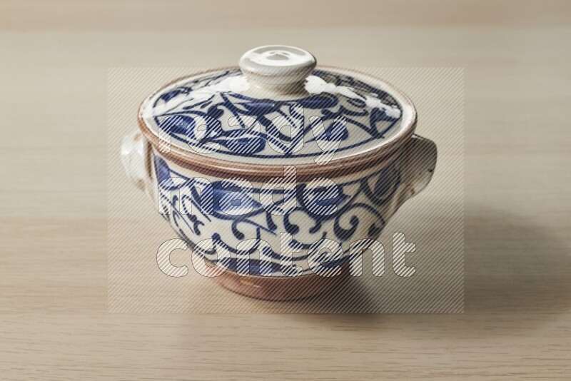 A multicolored pottery pot on light wooden background