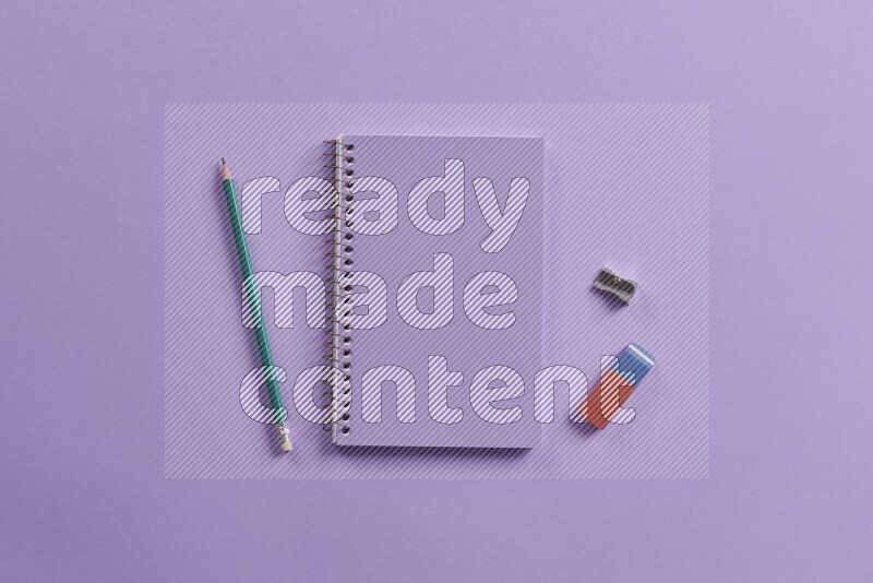 A purple notebook with different school supplies on purple background