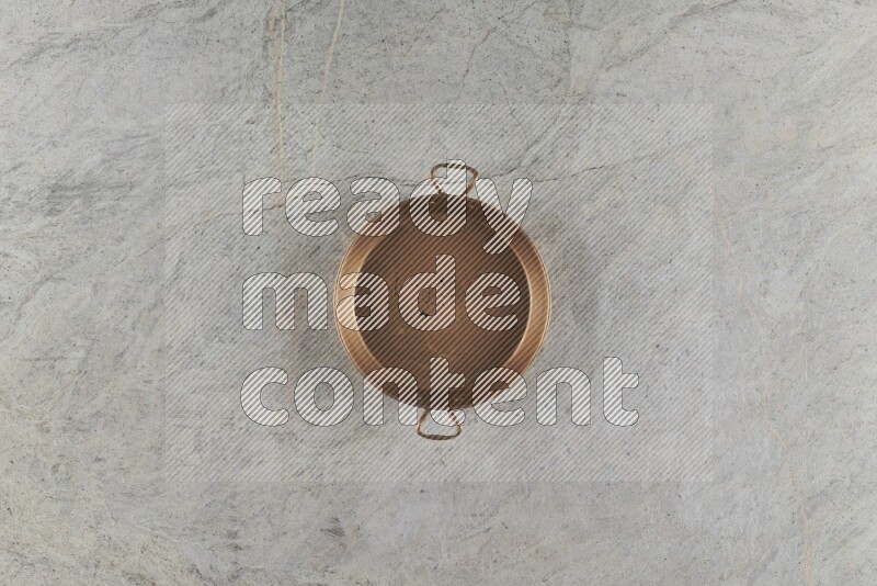 A small copper pan on grey marble background