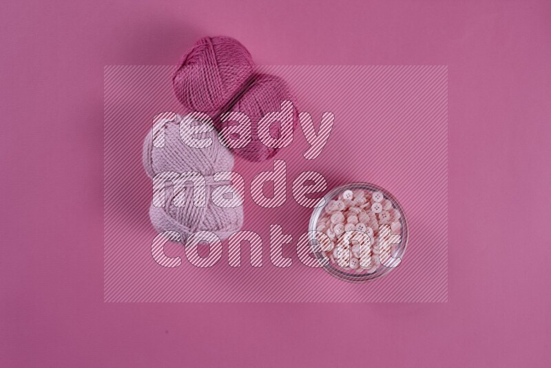 A pink collection of sewing and tailoring tools arranged on a pink background