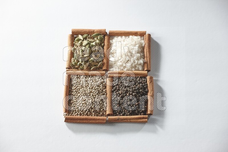 4 squares of cinnamon sticks full of cardamom, salt, white pepper and black pepper on white flooring