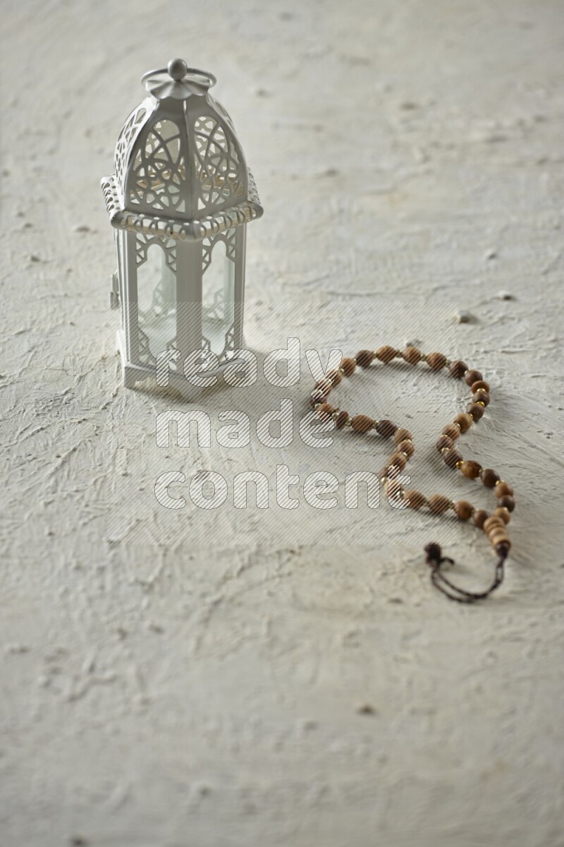 A white lantern with different drinks, dates, nuts, prayer beads and quran on white background