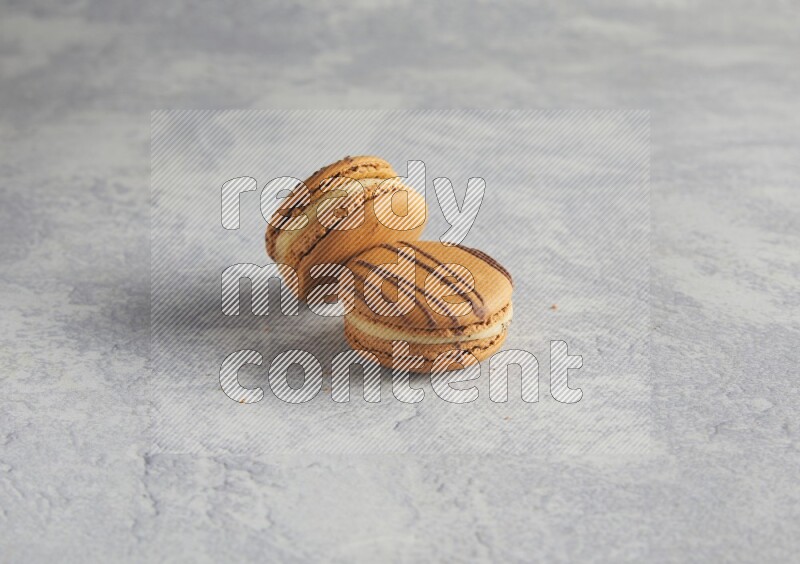 45º Shot of two light brown  Almond Cream macarons  on white  marble background