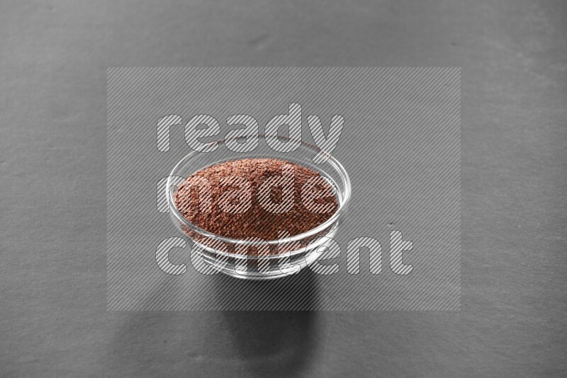 A glass bowl full of garden cress on black flooring