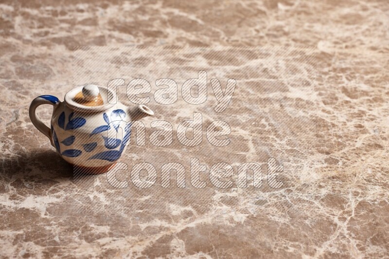 A pottery teapot on beige marble background