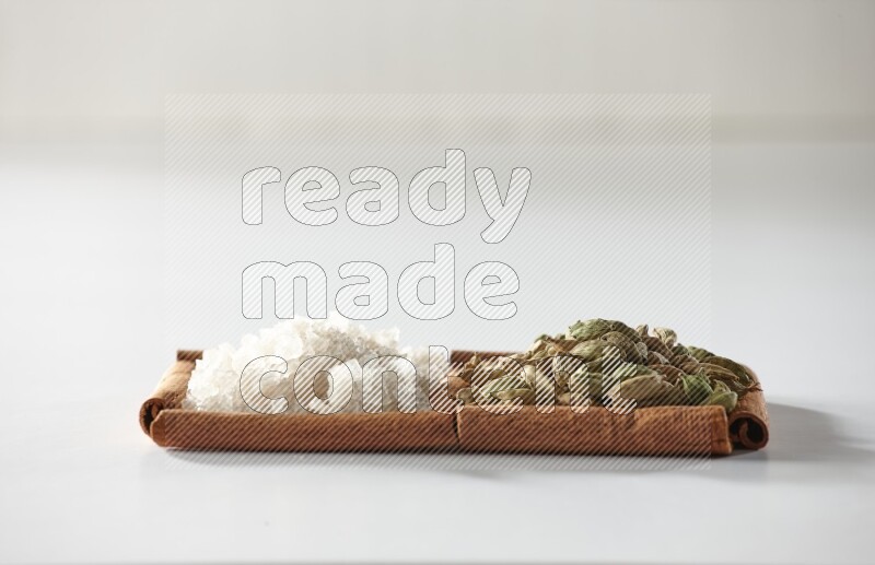 2 squares of cinnamon sticks full of cardamom and white salt on white flooring