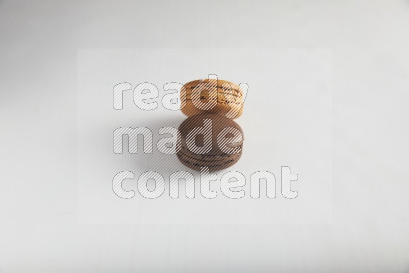 45º Shot of of two assorted Brown Irish Cream, and Brown Dark Chocolate macarons on white background