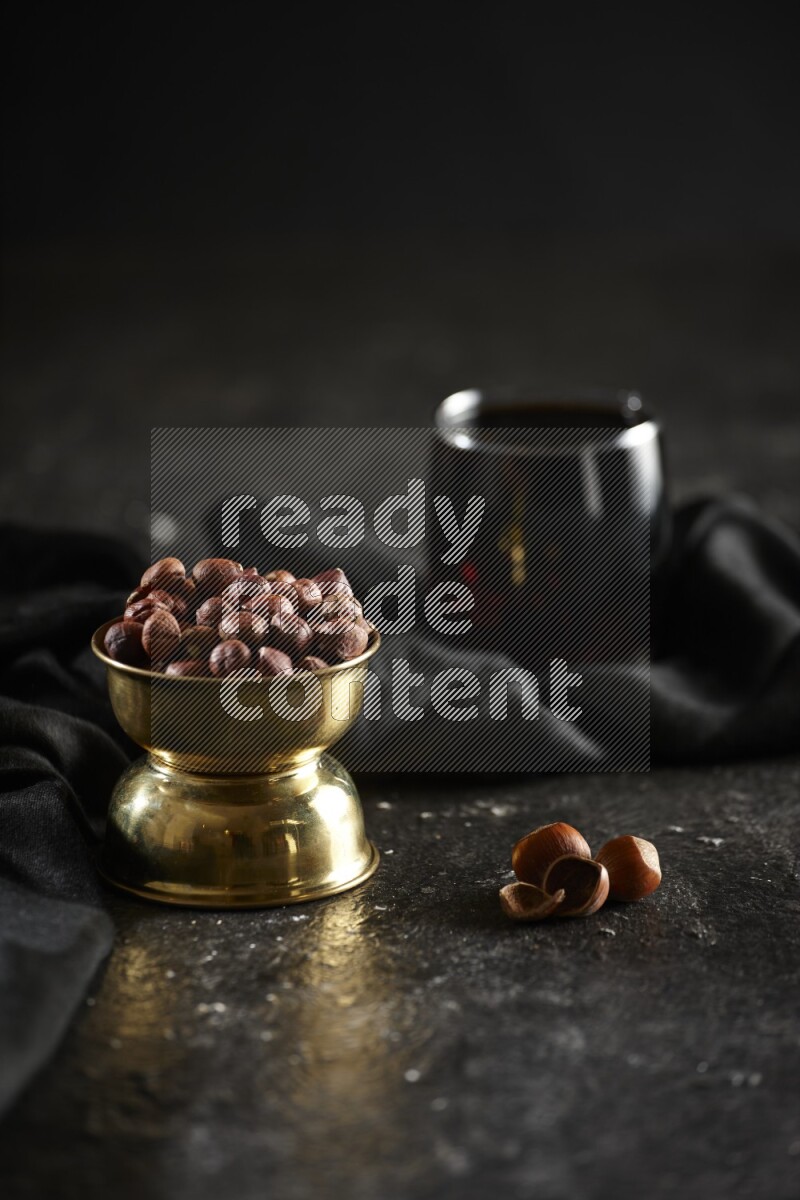 Nuts in a metal bowl with tamarind and a napkin in a dark setup