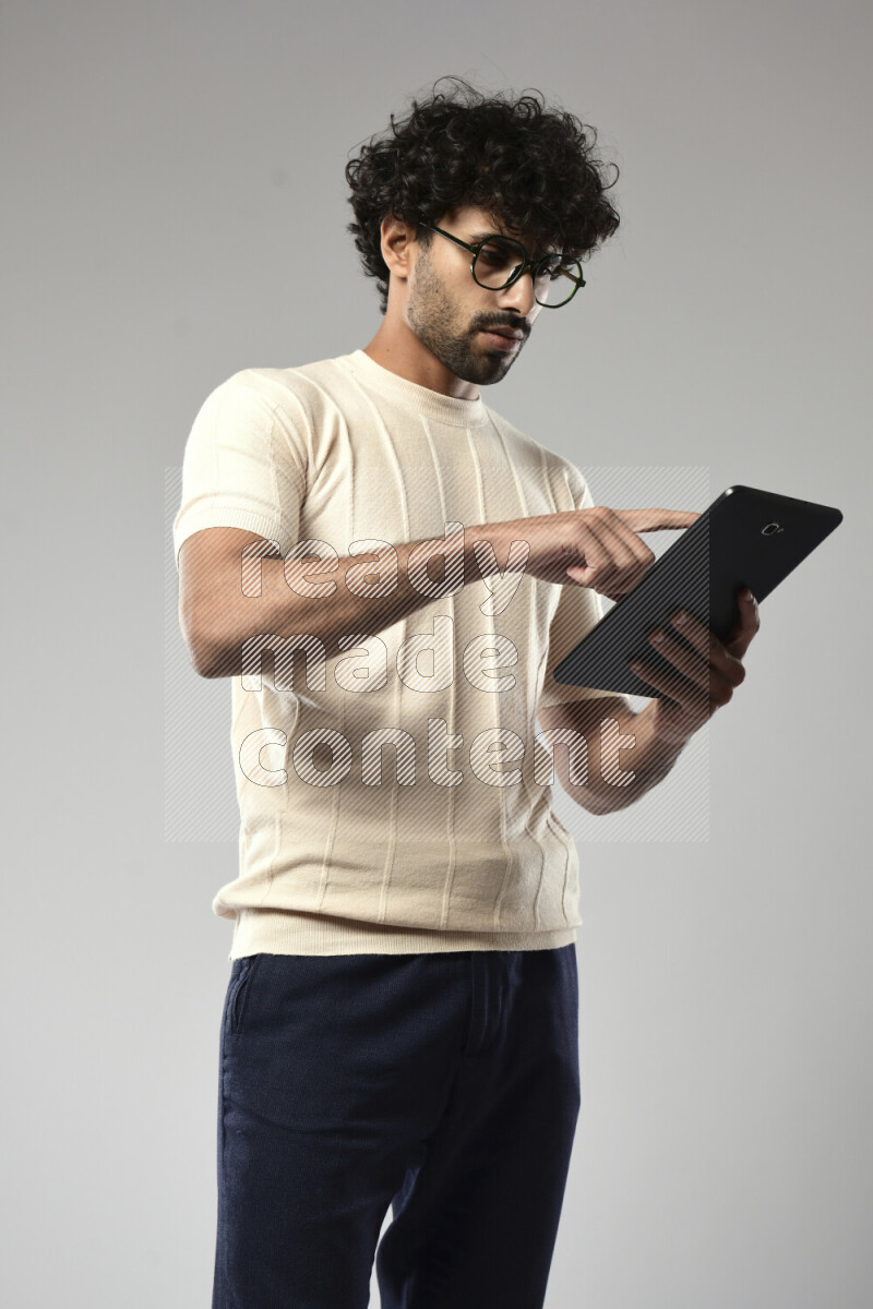 A man wearing casual standing and browsing on a tablet on white background