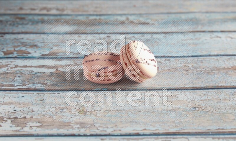 45º Shot of two pink orange blossom macarons on light blue wooden background