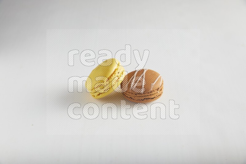 45º Shot of of two assorted Brown Irish Cream, and Yellow Lemon macarons on white background
