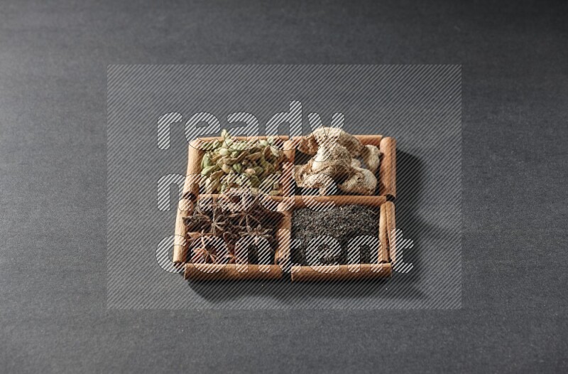4 squares of cinnamon sticks full of tea, star anise, dried ginger and cardamom on black flooring