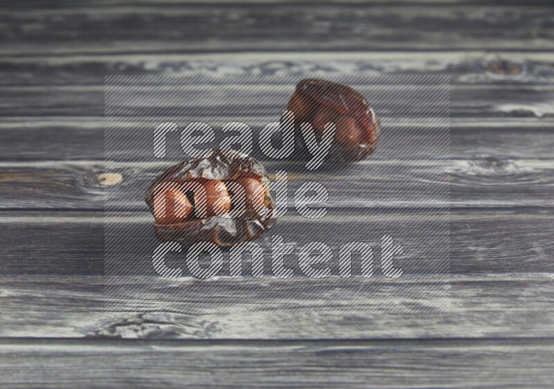 two hazelnut stuffed madjoul dates on a wooden grey background