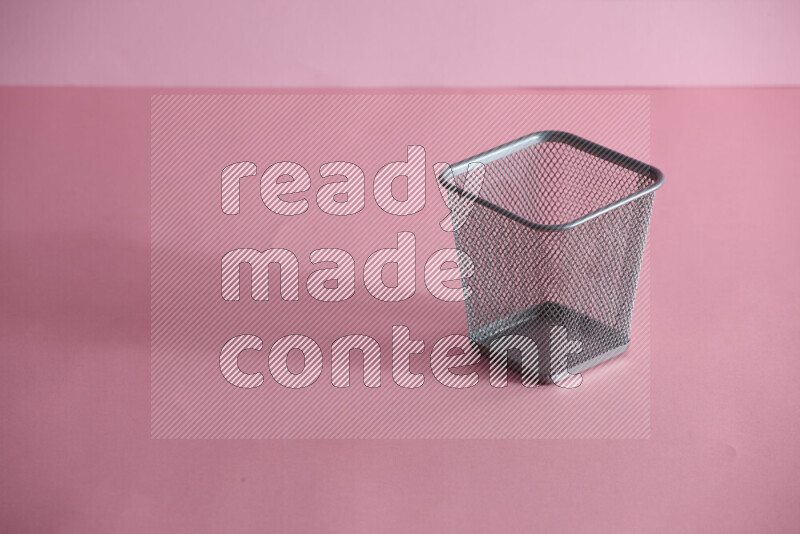 Pens, pencils and other different school supplies in a metal pen holder on rose background