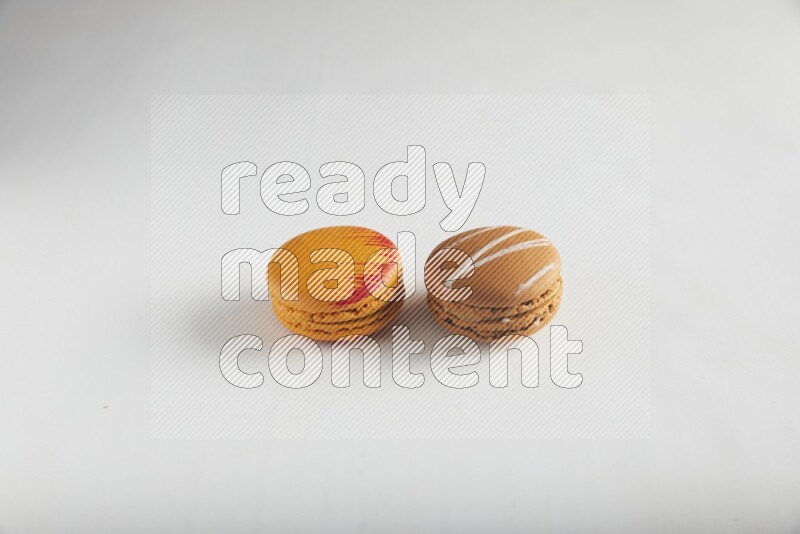 45º Shot of of two assorted Brown Irish Cream, and Orange Exotic macarons on white background