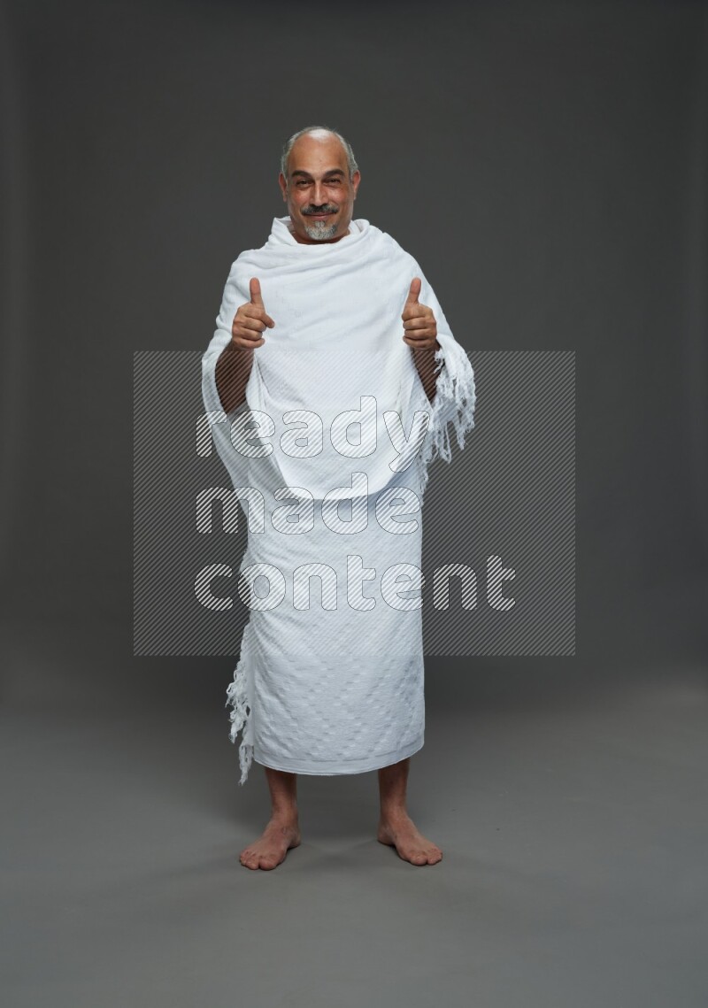 A man wearing Ehram Standing Interacting with the camera on gray background